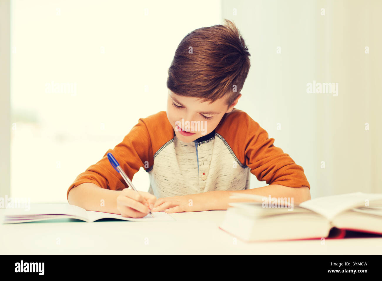 Ребенок любит писать. Тетрадки для детей. Мальчик пишет за столом. Ребенок пишет. Писающий мальчик.