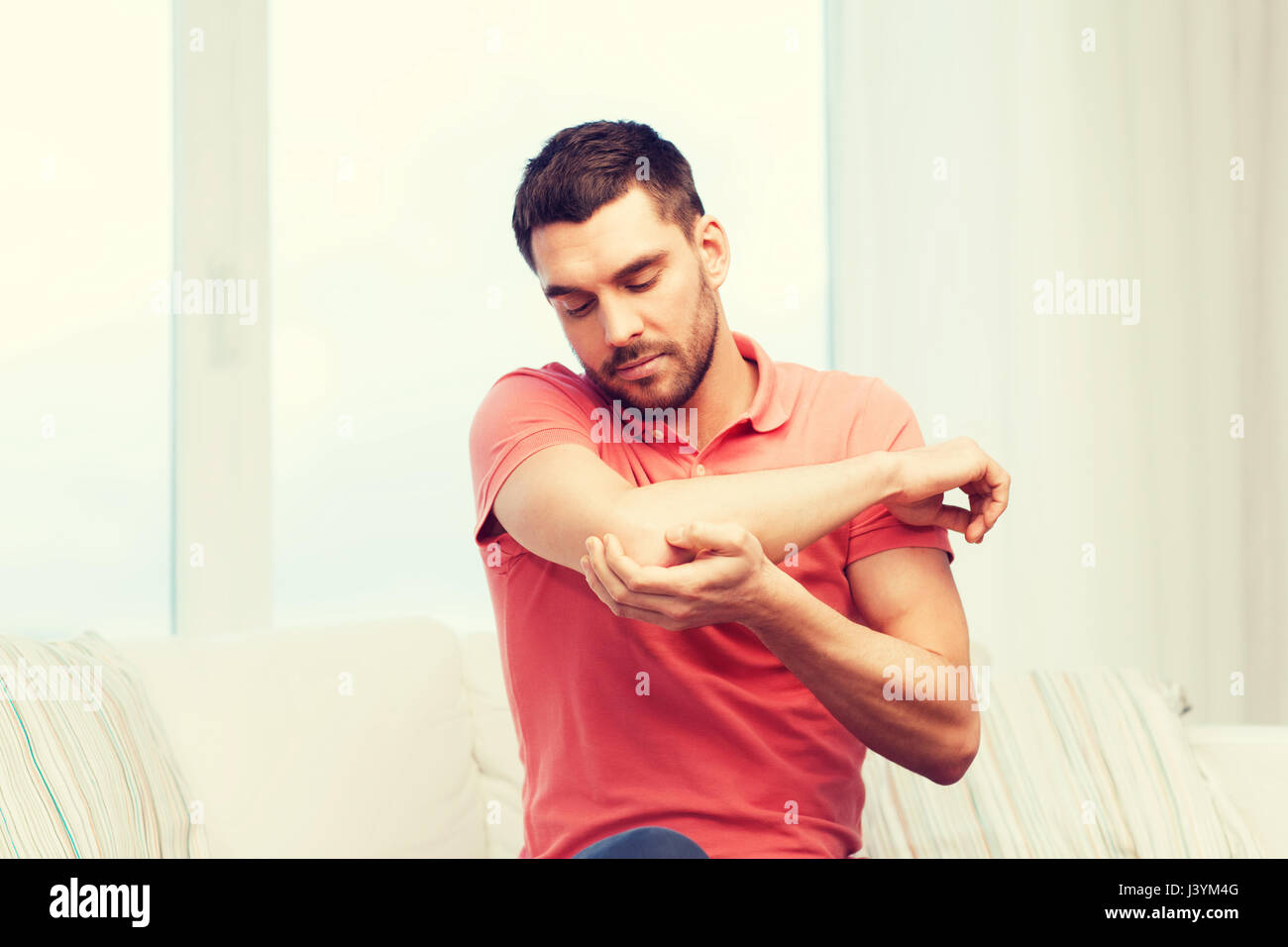 unhappy man suffering from pain in hand at home Stock Photo - Alamy