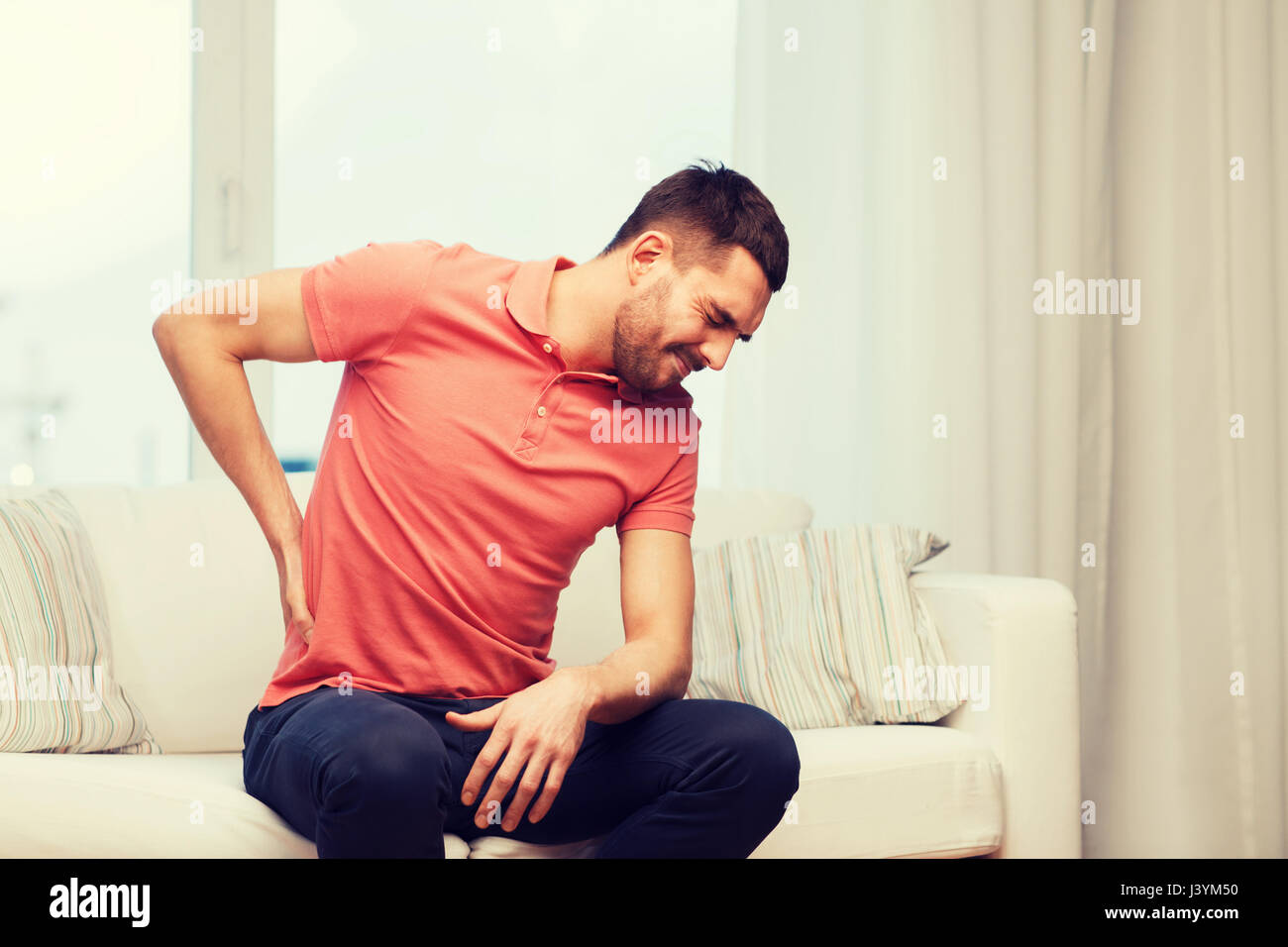 unhappy man suffering from backache at home Stock Photo - Alamy