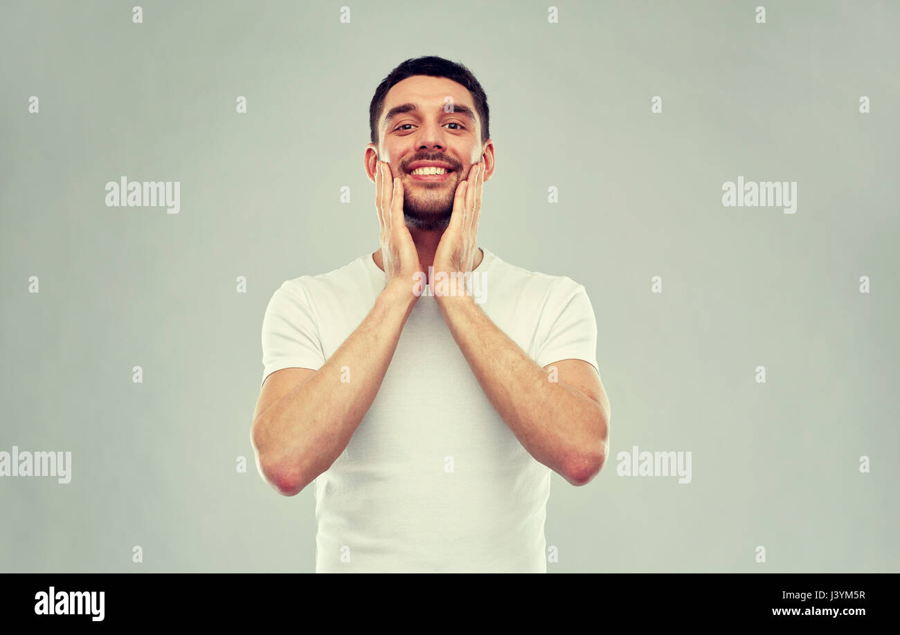 happy young man applying aftershave to face Stock Photo