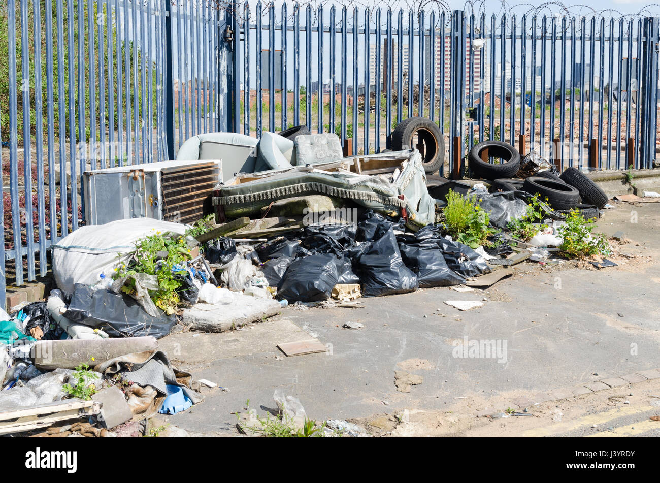Pile of rubbish resulting from fly tipping including car tyres and sofa Stock Photo
