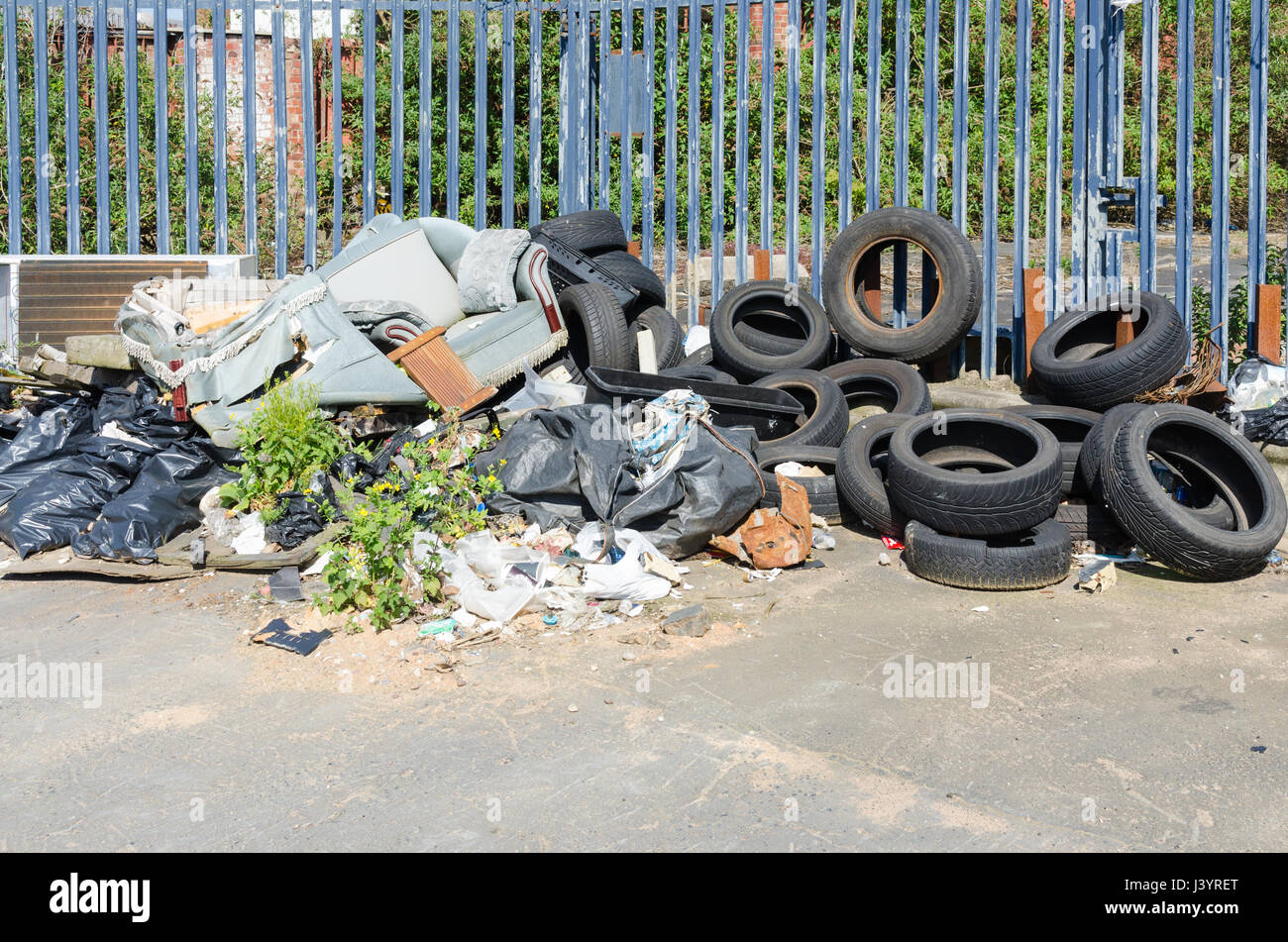 Pile of rubbish resulting from fly tipping including car tyres and sofa Stock Photo