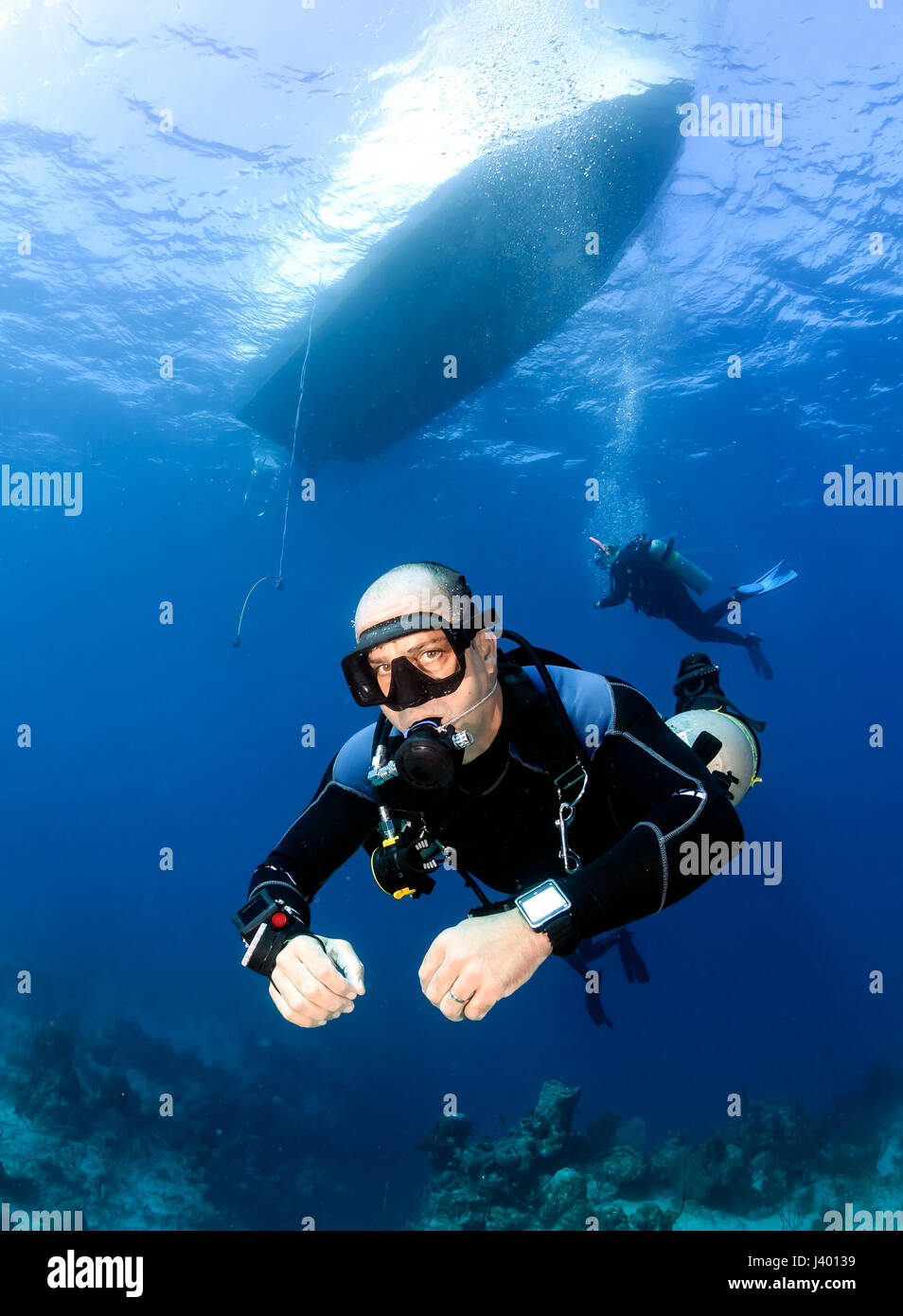 SCUBA diver in a technical sidemount cofiguration underneath a dive boat Stock Photo