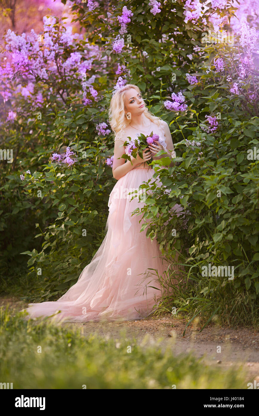 Beautiful woman enjoying lilac garden, young woman with flowers in ...