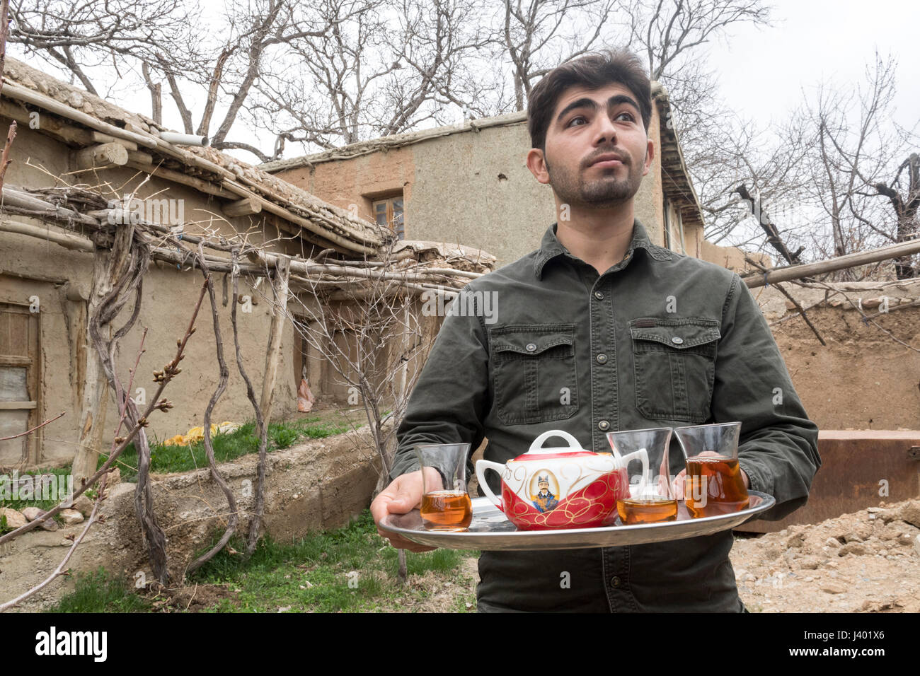 Ali, A Guesthouse Owner Holding A Tray With A Teapot Decorated WIth The Image of Qajar King Nasseredin Shah, Rooieen (Ruin), A Traditional Rural Villa Stock Photo