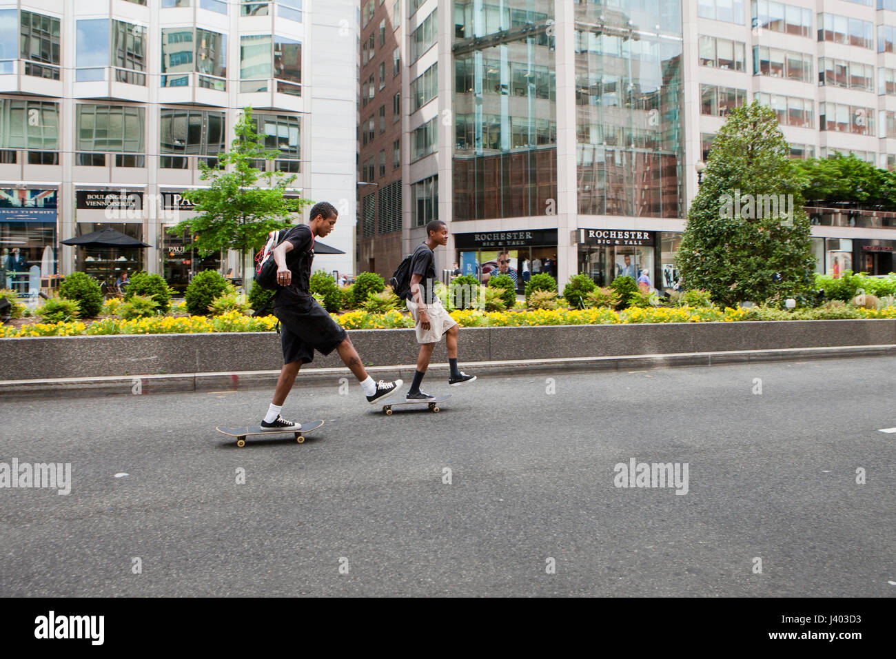 Young skateboarders riding in city street - USA Stock Photo