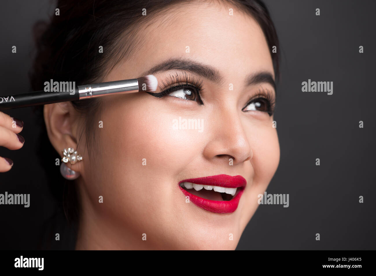 Close up of hand of asian woman applying eyeshadow on female eyelid. Stock Photo