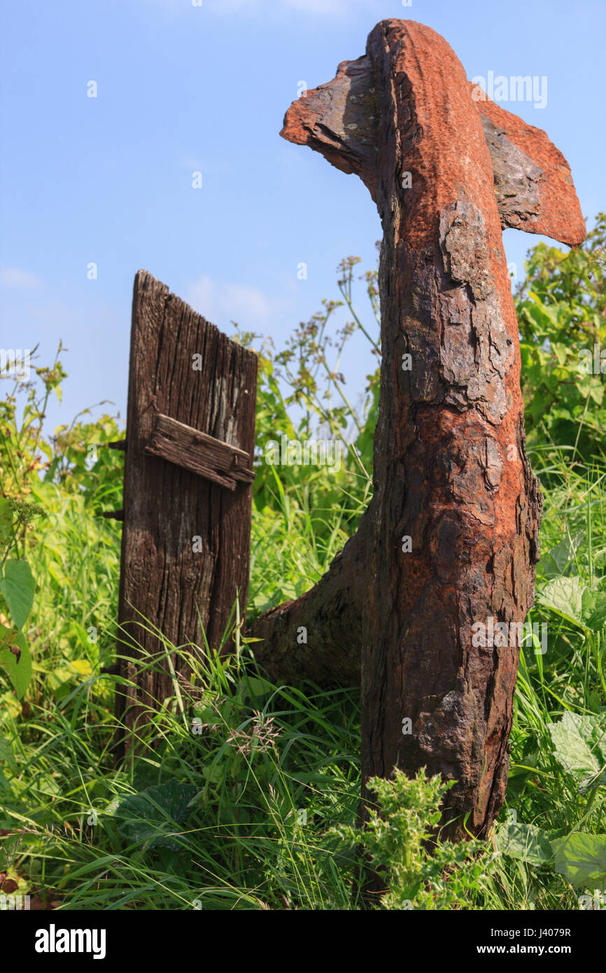 Old rusty ships anchor in the grass against a blue sky Stock Photo