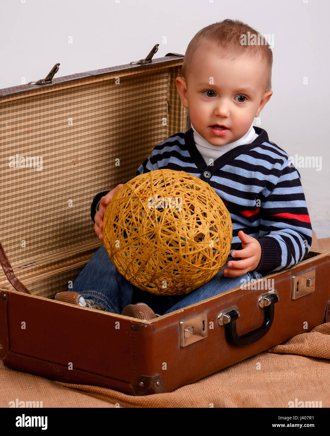 Two, three years old baby boy carry big suitcase isolated on a white background. transportation