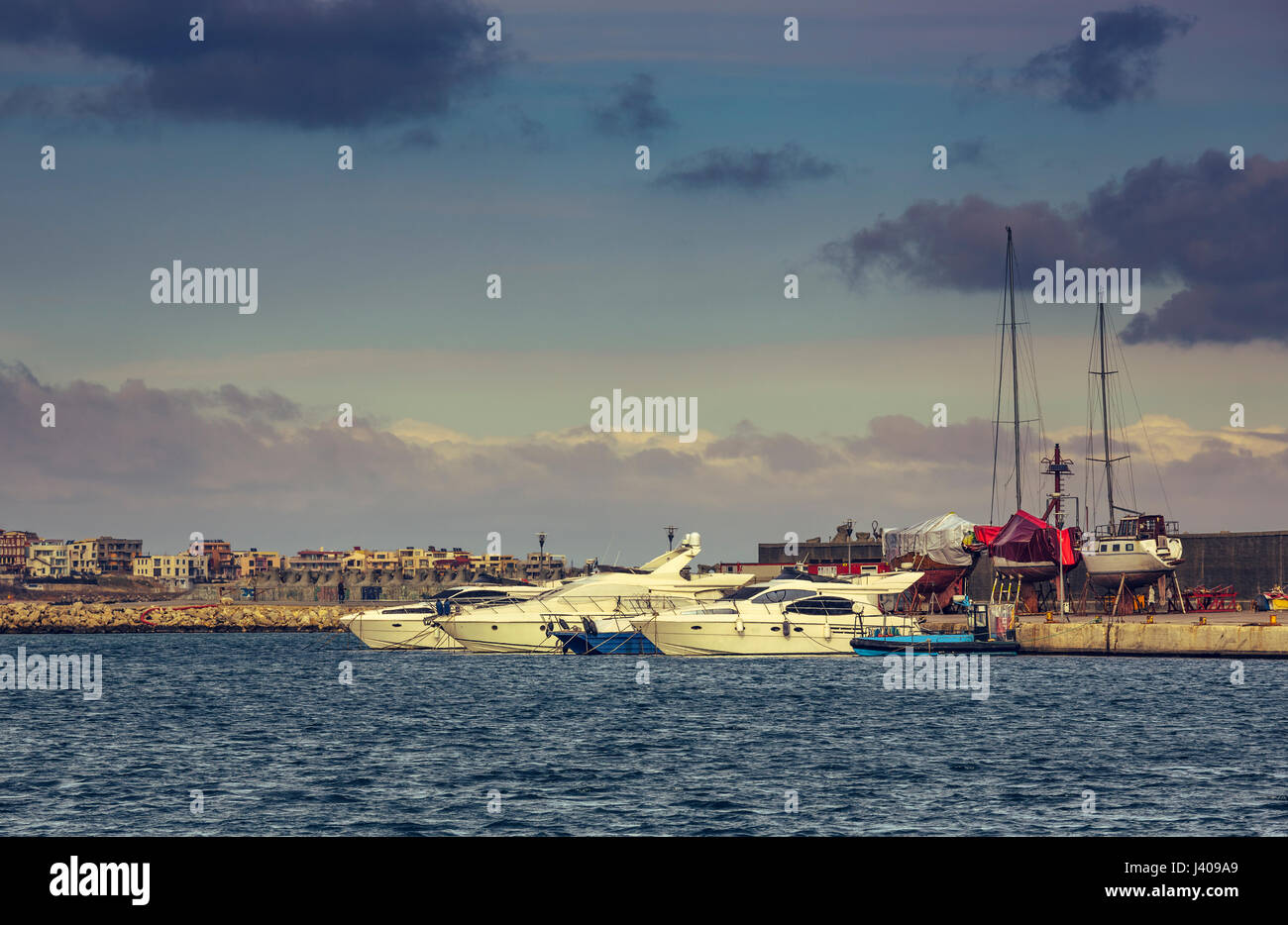 Sailing boats and modern yachts anchored in Tomis touristic harbour of Constanta sea port, in the evening, on the Black Sea shore, Romania. Stock Photo