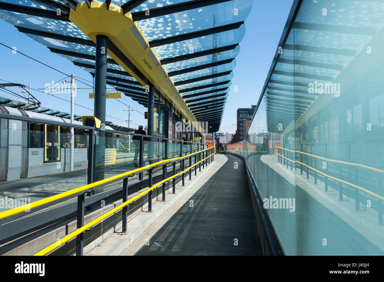 Metrolink tram and glass wall at the Deansgate-Castlefield tram stop, Manchester, England, UK Stock Photo