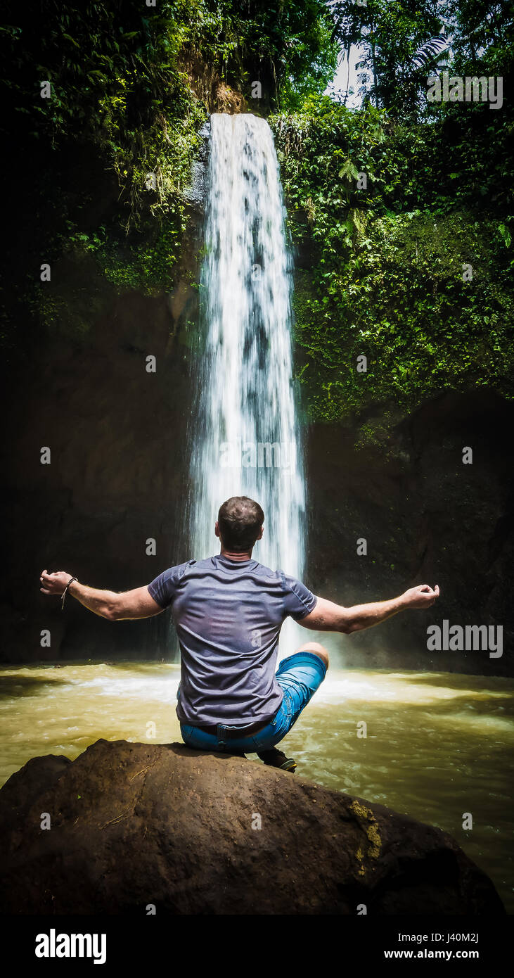 Man meditating in front of waterfall near Ubud, Bali, Indonesia Stock Photo