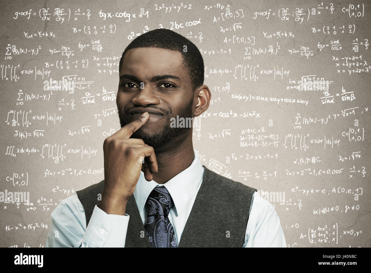 Closeup portrait young confused business man finger on lips, thinking deeply about something, looking puzzled, isolated black, grey background math fo Stock Photo