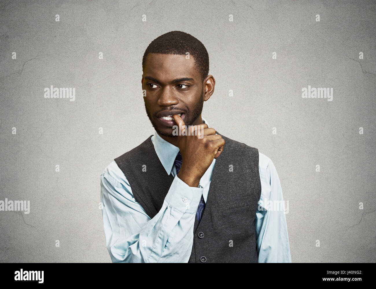 Closeup portrait, Man with Finger in Mouth, Sucking Thumb, biting fingernail in Stress, deep thought, isolated black, grey wall background. Negative h Stock Photo