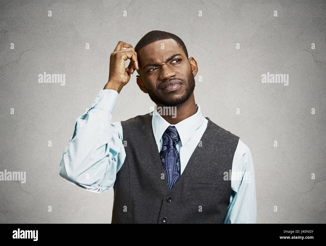 Closeup portrait young company business man thinking, daydreaming trying hard to remember something looking upward, isolated black background. Negativ Stock Photo