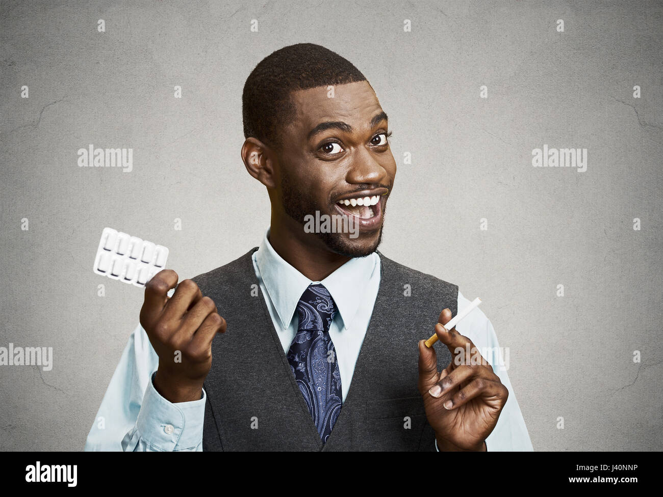 Closeup portrait, headshot happy man offering Help with Cigarette Addiction, nicotine chewing gum, isolated grey wall background. Face expressions. He Stock Photo