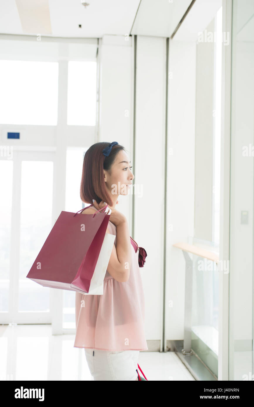 Young woman with shopping bags in shopping center Stock Photo - Alamy