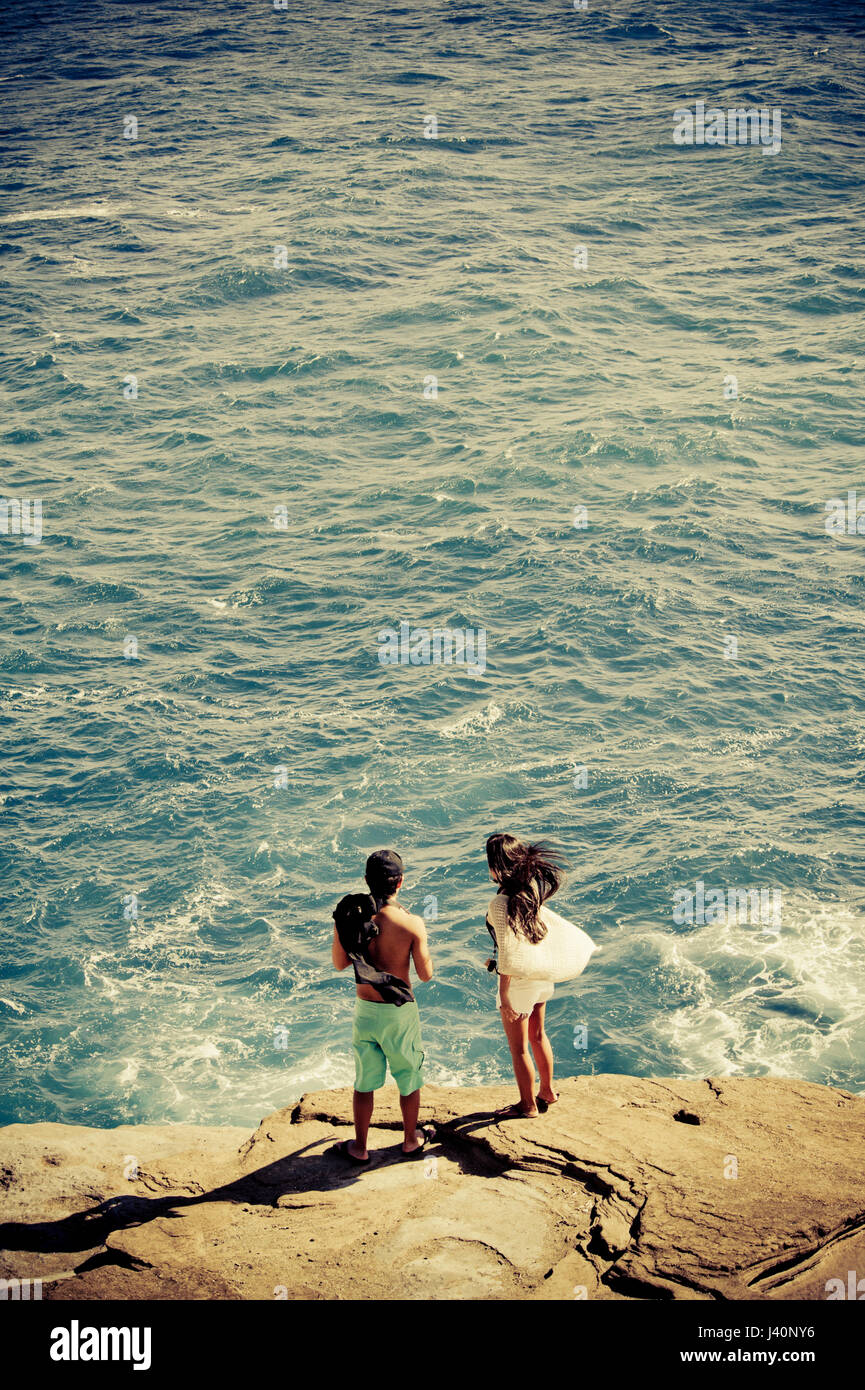 Young couple standing on the edge of a rock by the ocean near Honolulu, Hawaii Stock Photo
