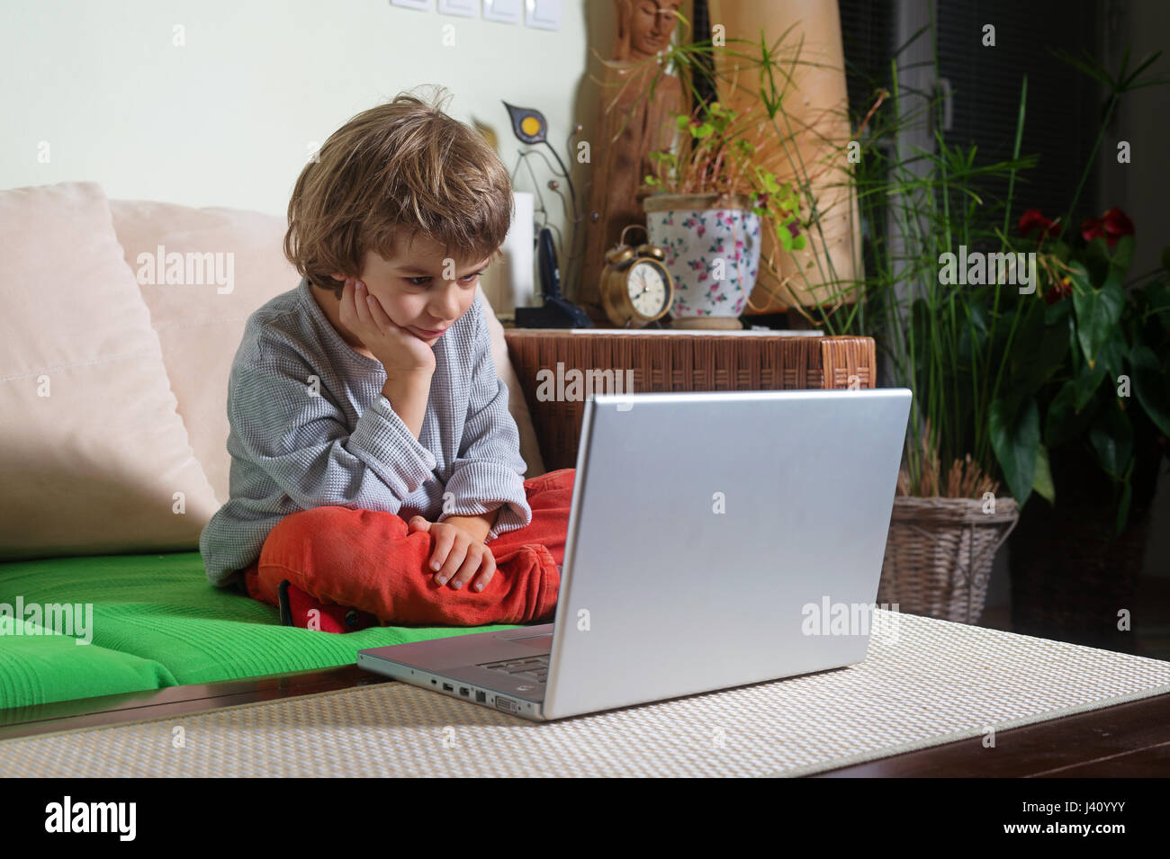 Little boy on sofa amused by scene on laptop Stock Photo - Alamy