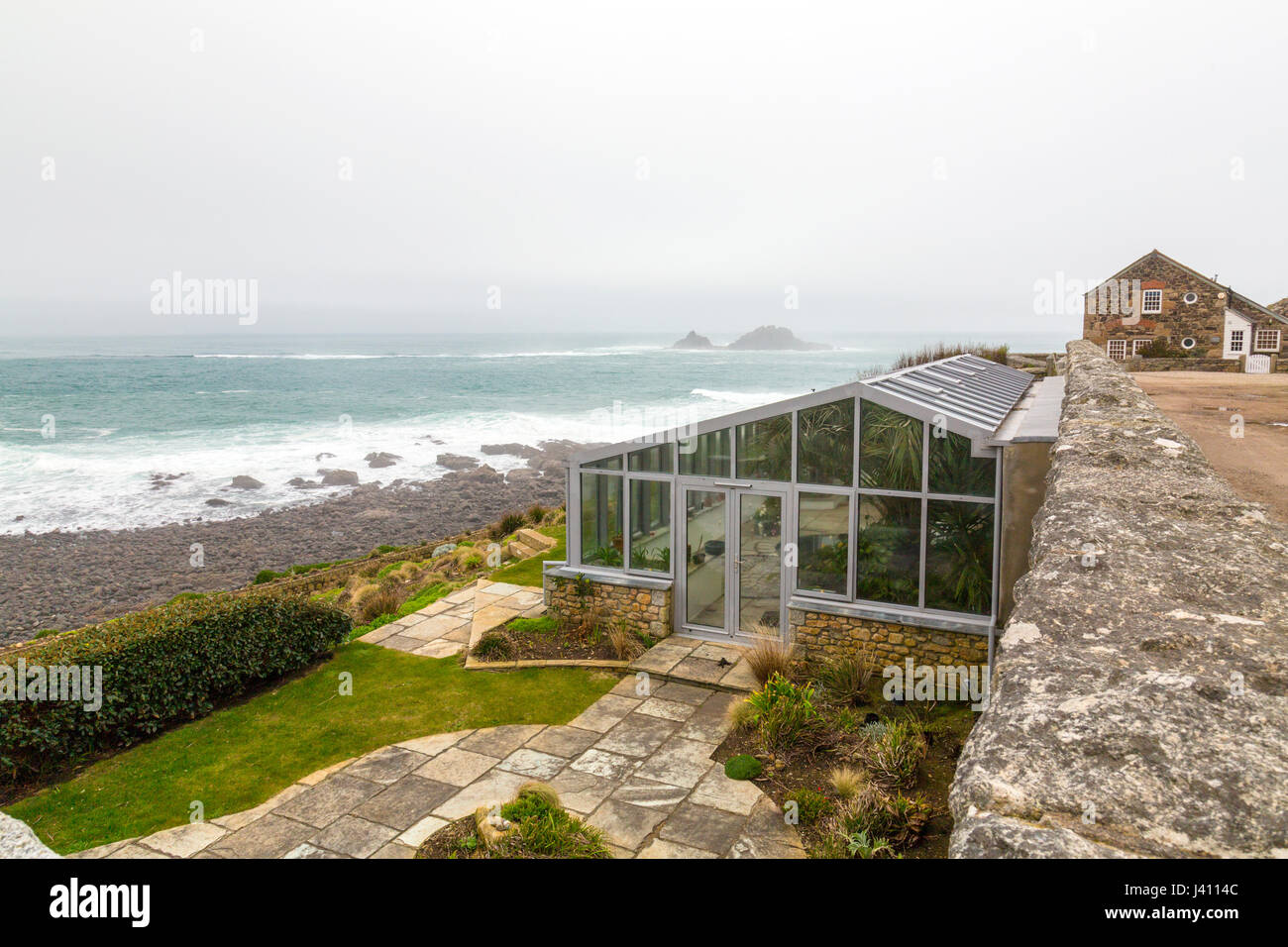 A lean-to glasshouse at Cape Cornwall, Cornwall, England, UK.  Beyond are the notorious Brisons rocks, scene of many Cornish shipwrecks. Stock Photo