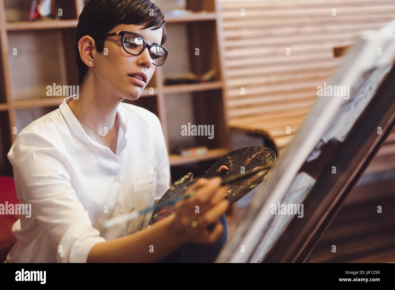 Female artist painting with palette and paintbrush on canvas Stock ...