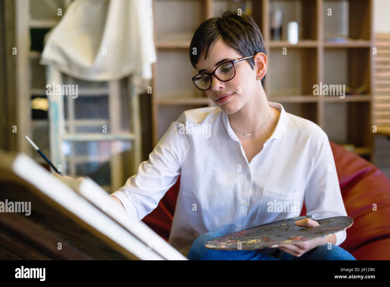 Female artist painting with palette and paintbrush on canvas Stock ...