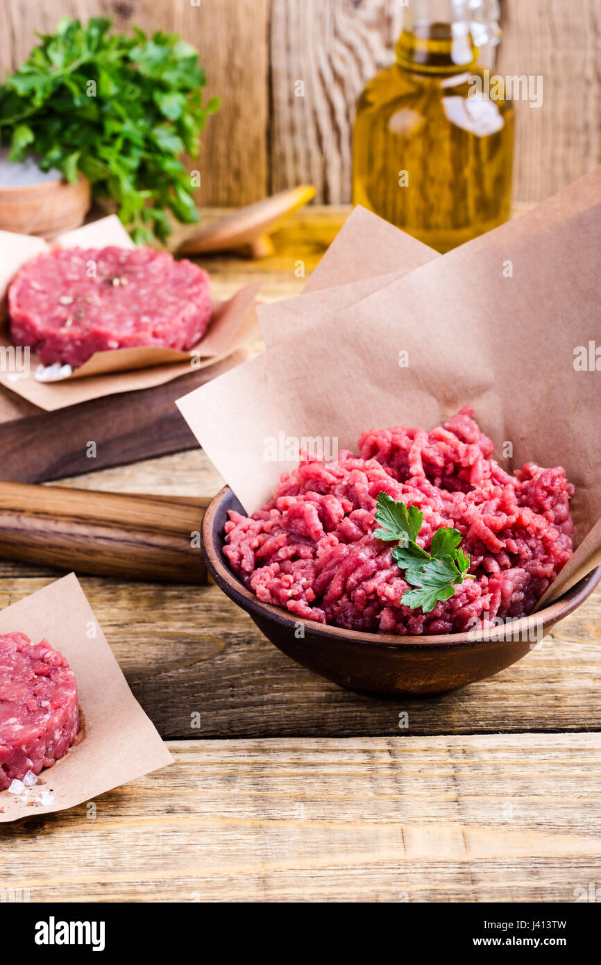 Organic raw ground beef meat and burger steak cutlets ready to prepare on rustic table Stock