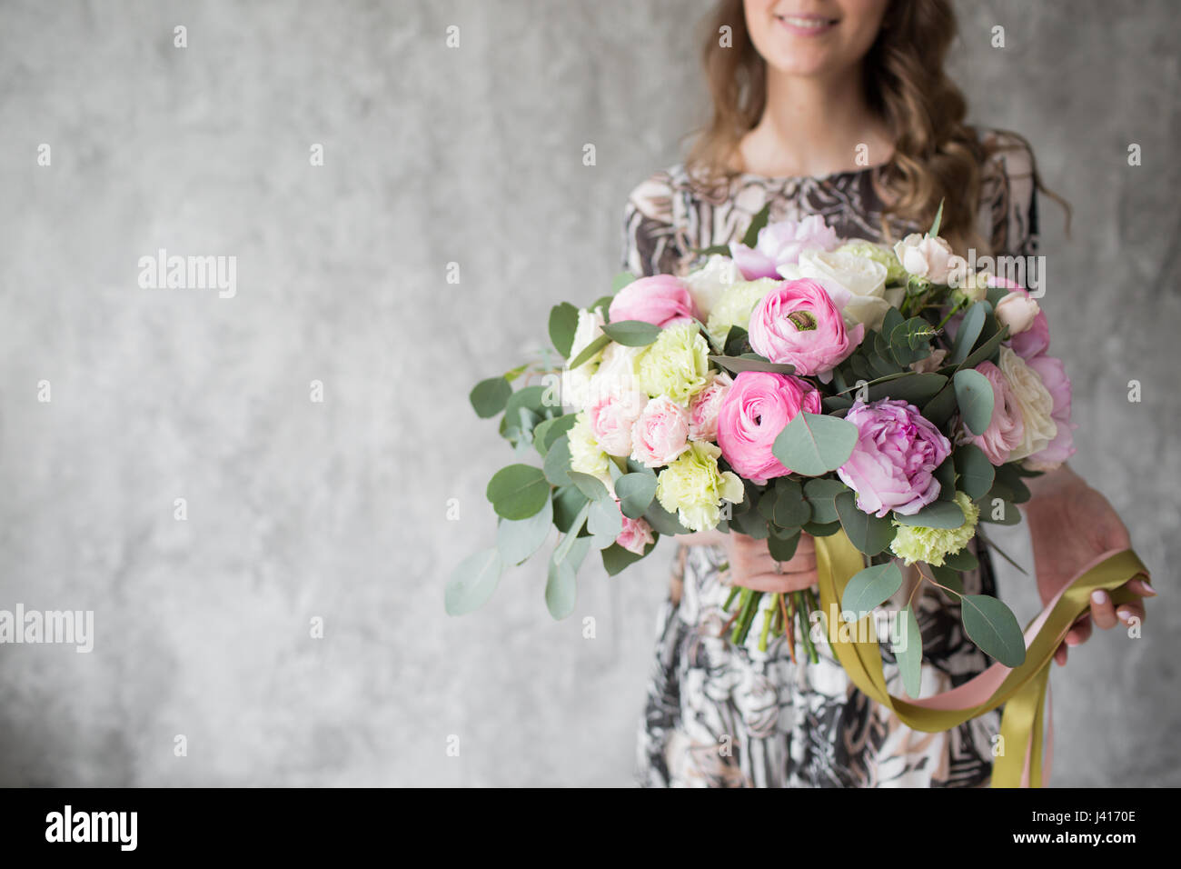 Happy beautiful young woman holding bouquet of mixed flowers standing ...