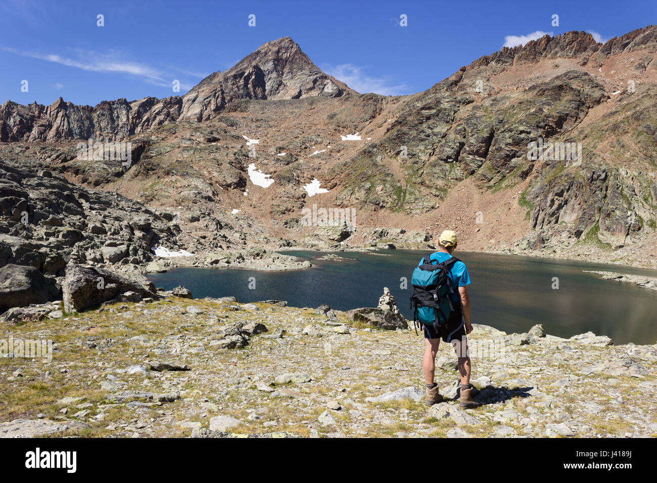 Hiking in Aosta valley, Italy. Hiker gazes at third lake of Lussert ...