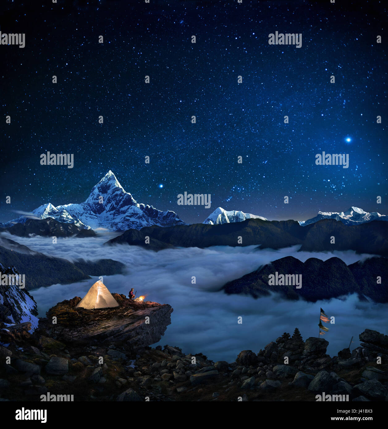 Night sky over snowcapped mountains, Man camping near prayer flags, Pokhara, Kaski, Macchapucchare, Annapurna, Nepal, Asia Stock Photo