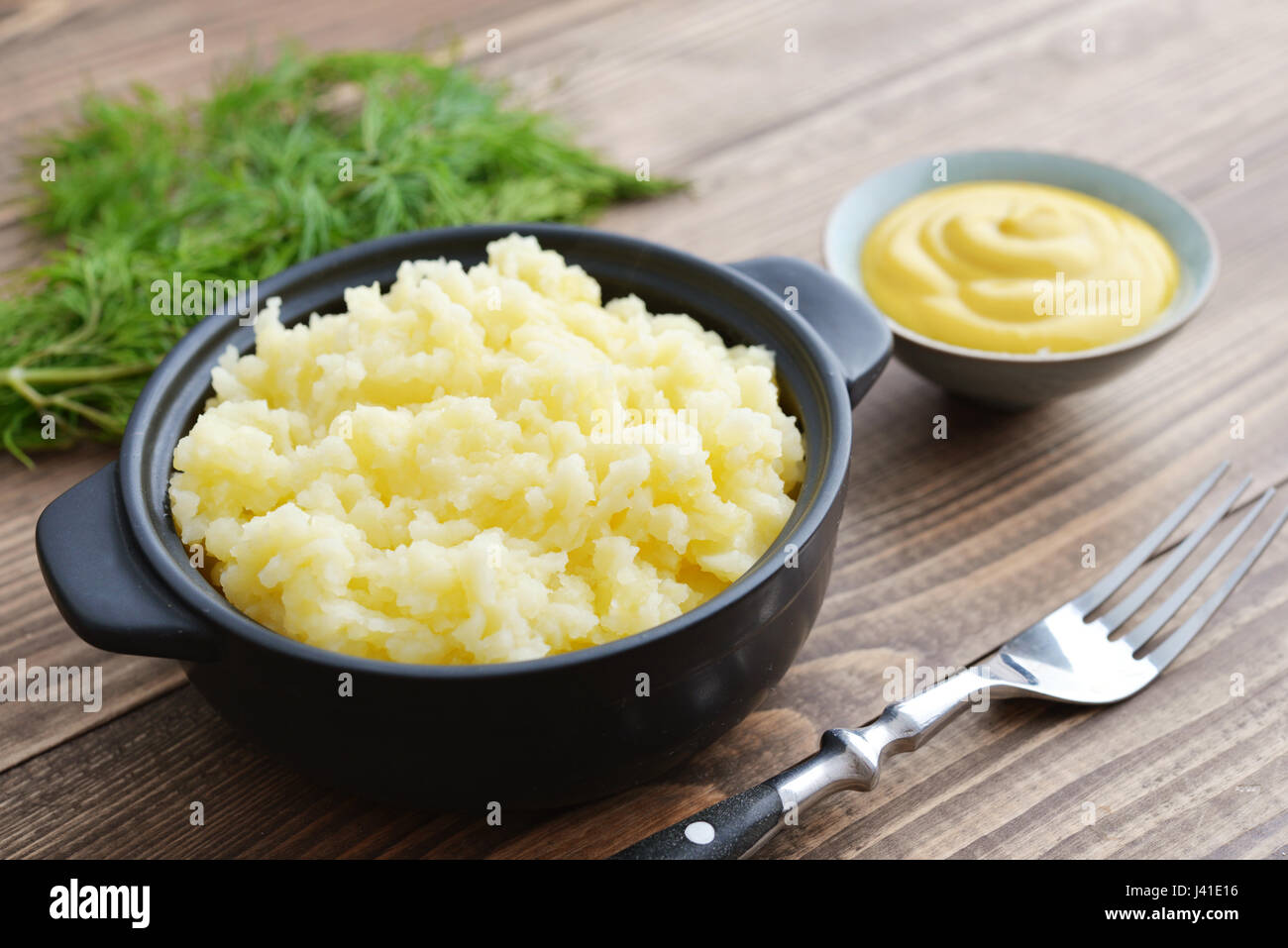 Mashed potatoes in bowl on wooden background closeup Stock Photo