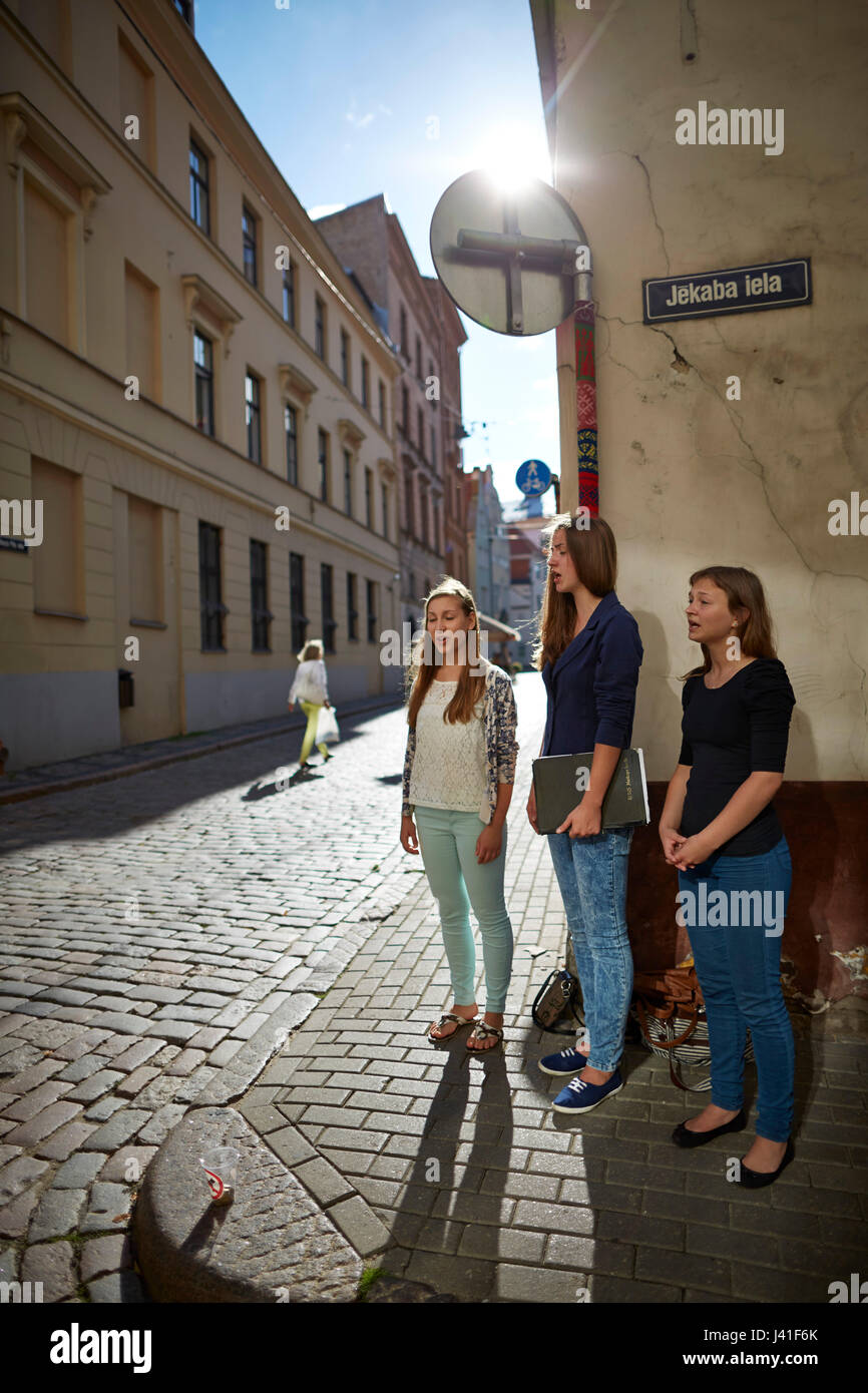 Three girlfriends Annija, Luize and Eliza singing for tourists, street choir on the corner of Jekaba and Maza Pils Iela, old town centre, Riga, Latvia Stock Photo