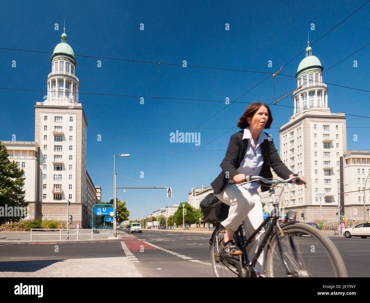 Cyclist rides past Frankfurter Tor apartment buildings on historic Karl Marx Allee in former East Berlin in Berlin, Germany Stock Photo