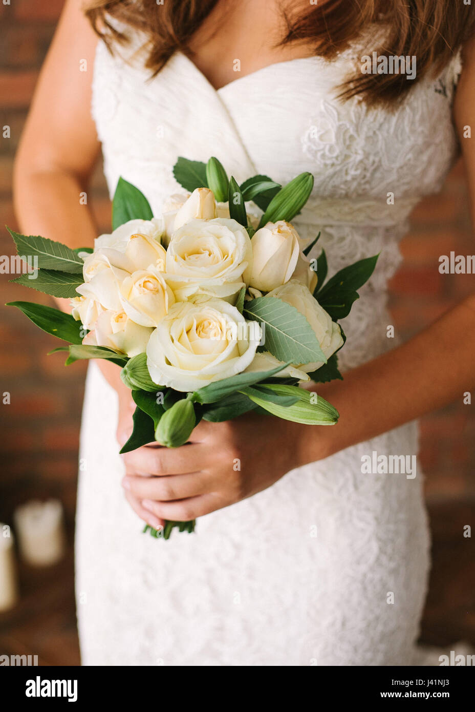 Beautiful woman in a white wedding dress holding a flowers bouquet from ...