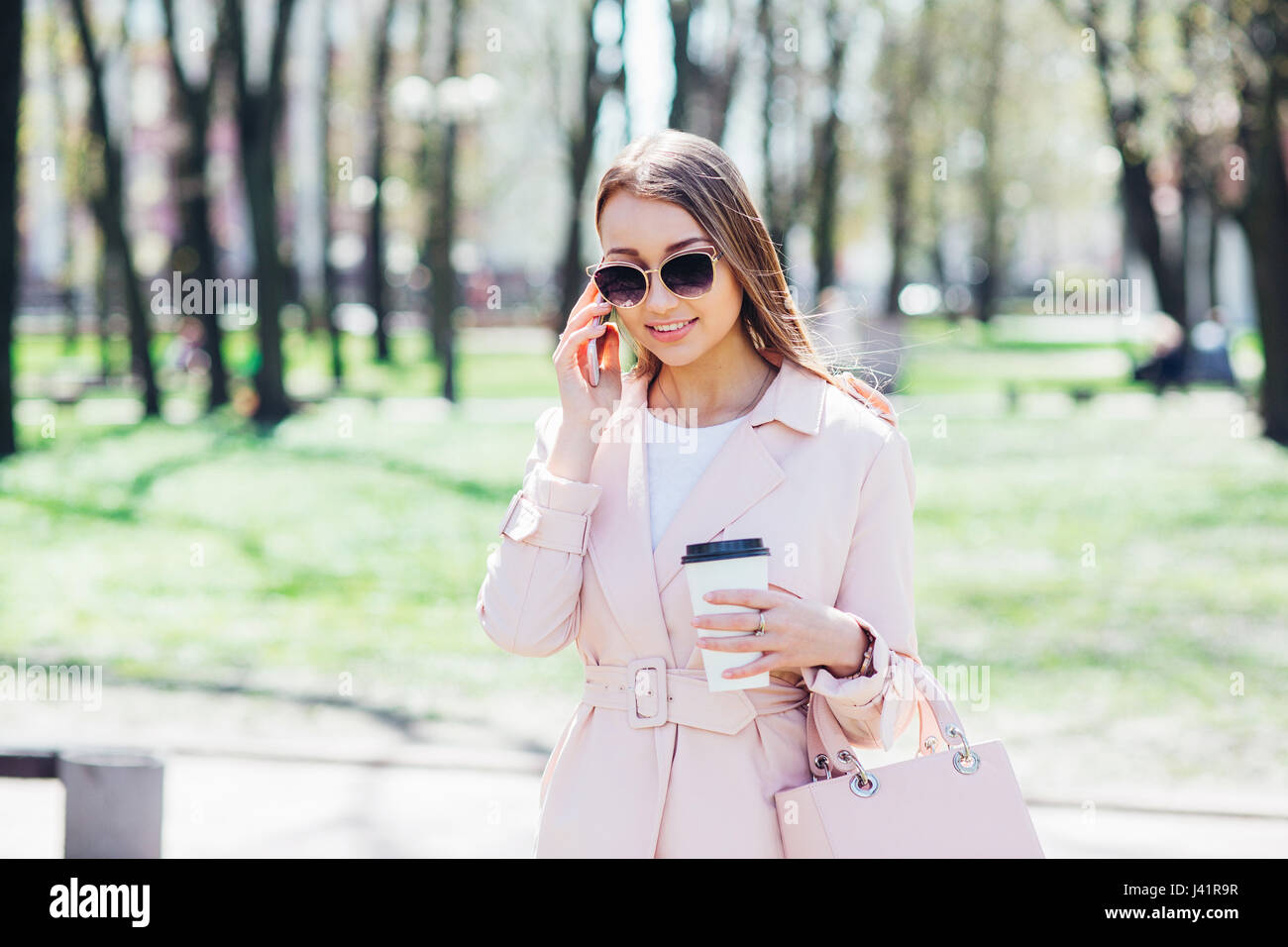 Fashionable woman with phone and cofee in the city. Stock Photo