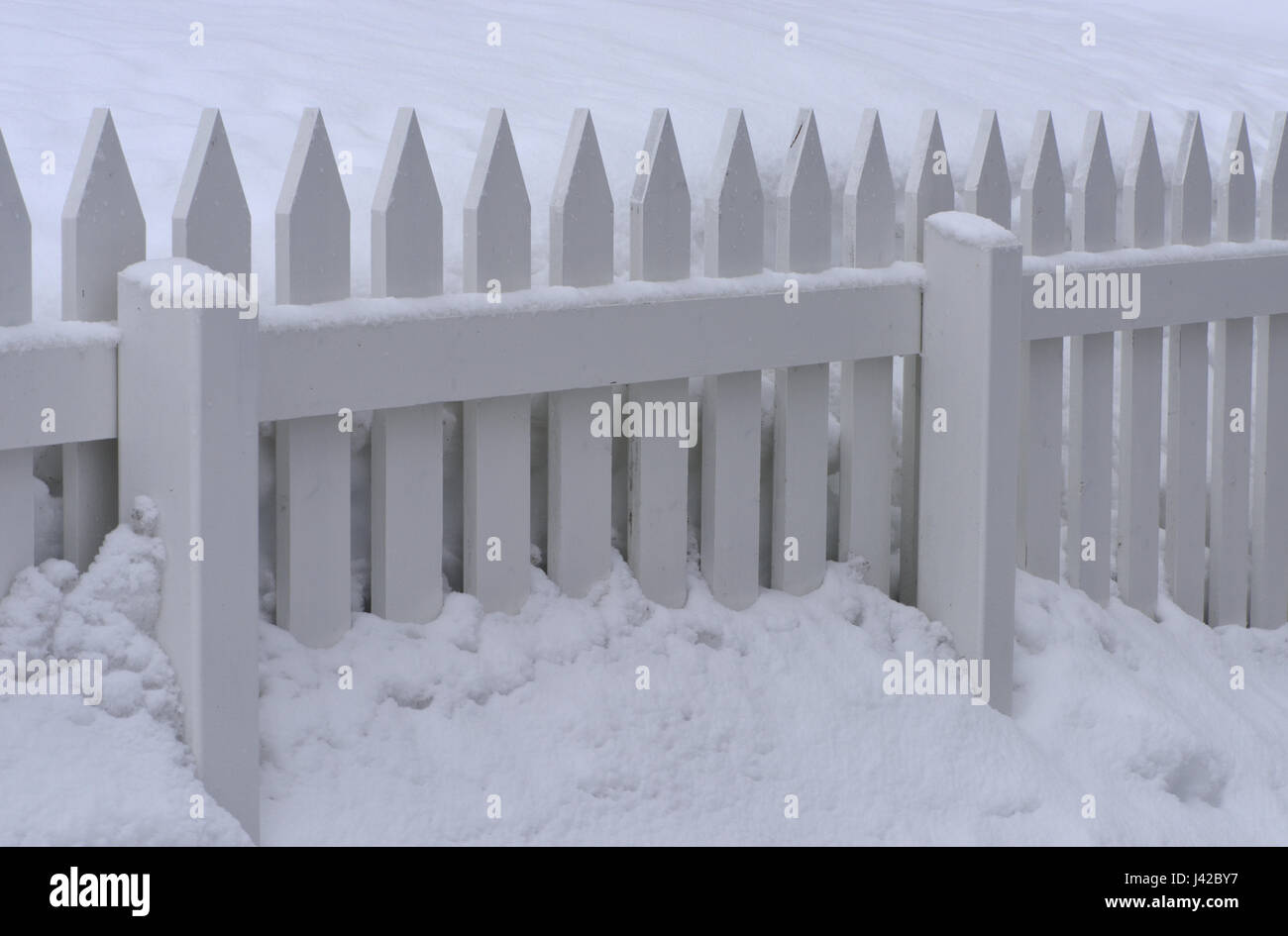 A white painted picket fence half buried in snow. Hammerfest, Finnmark, Norway. Stock Photo