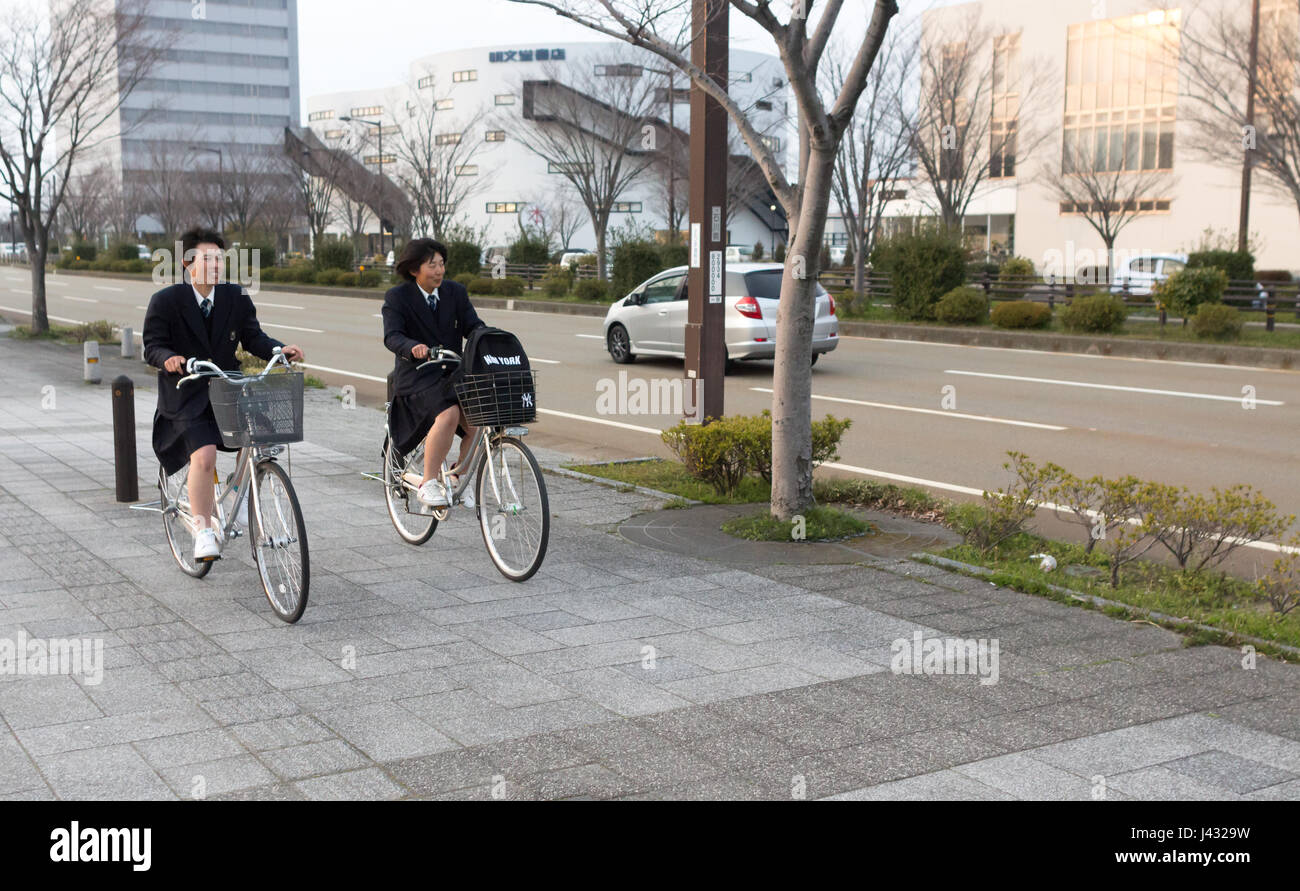 Kanazawa, Japan - March 30th, 2017: Two school girls riding a bicycle at Ishikawa-ken, Kanazawa-shi, Tomizu, 1 Chome. Stock Photo
