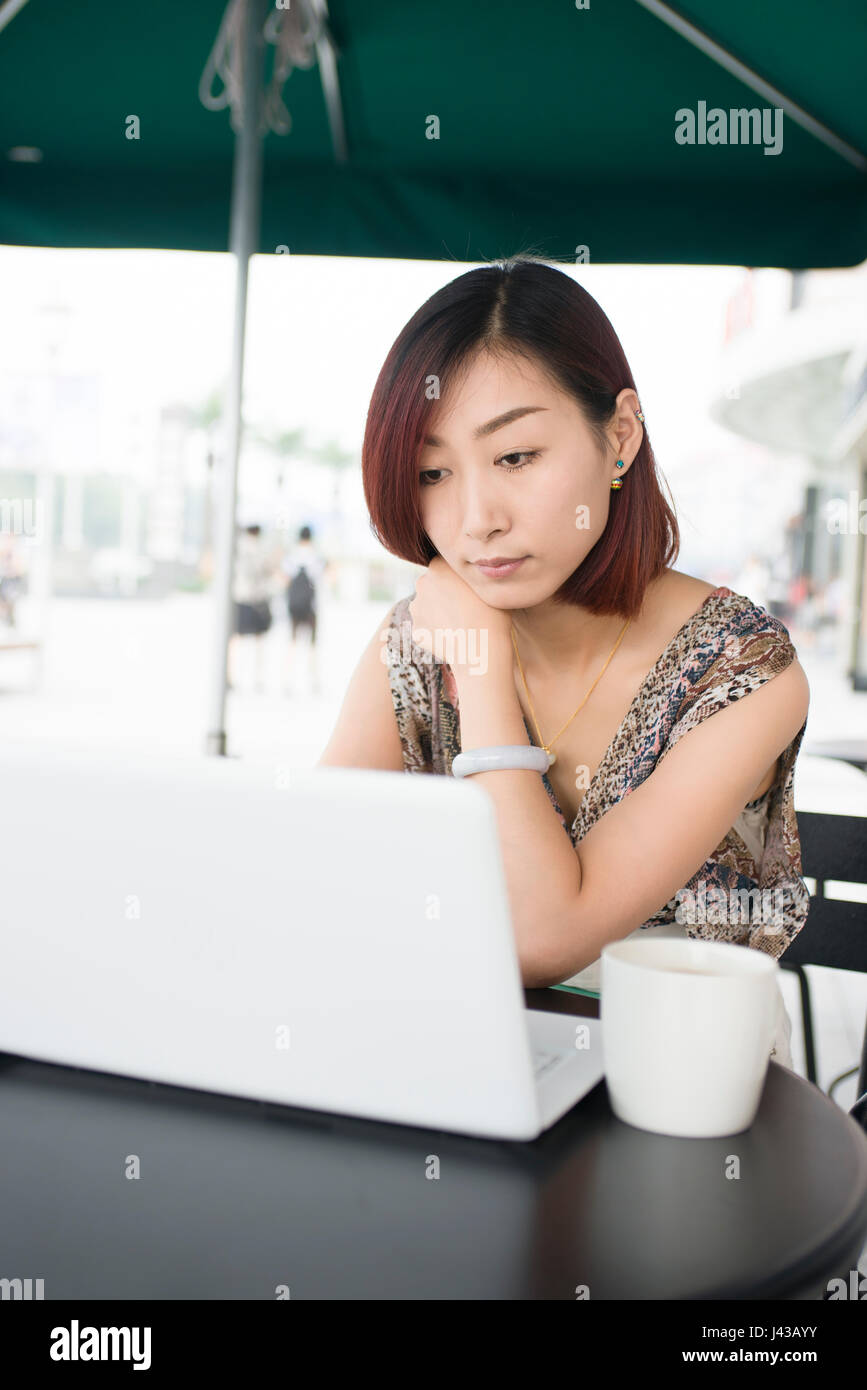 Young woman using her laptop sitting in outdoor cafe Stock Photo - Alamy
