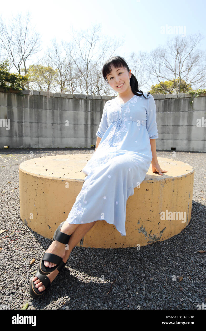 Portrait of young japanese woman sitting on a bench Stock Photo