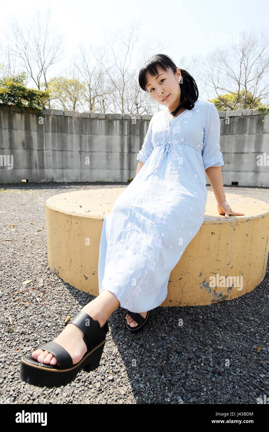 Portrait of young japanese woman sitting on a bench Stock Photo