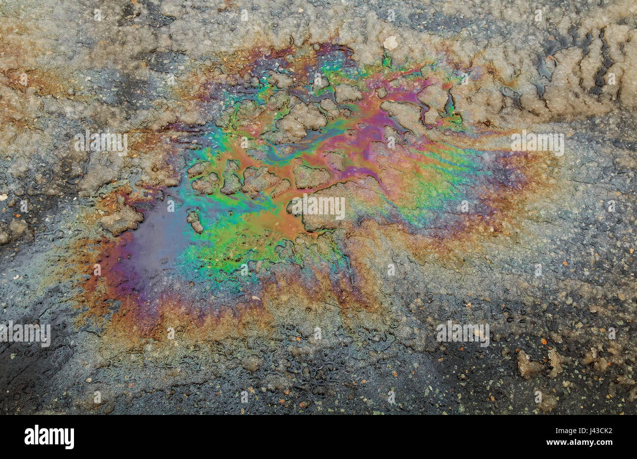 Puddled water polluted with fuel spill. gas spill in rainbow colors Stock Photo