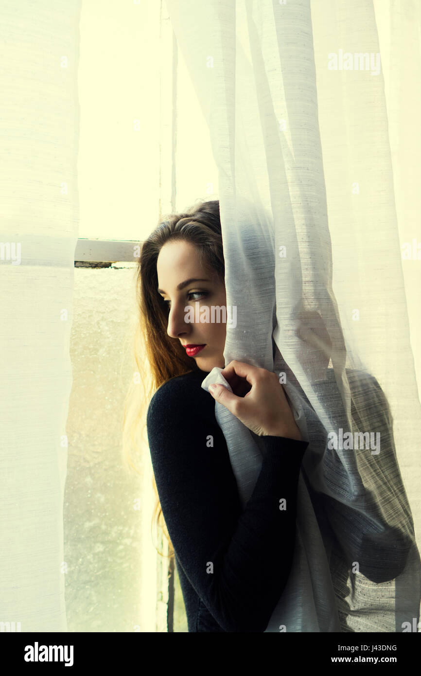 Worried young woman looking out of the window Stock Photo