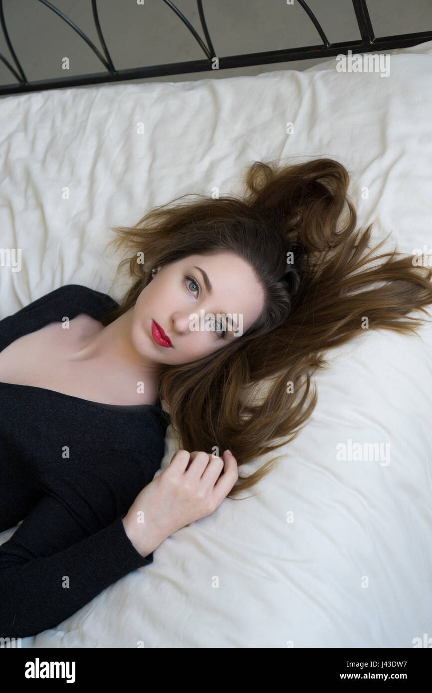 Beautiful young woman laying down in bed Stock Photo Alamy