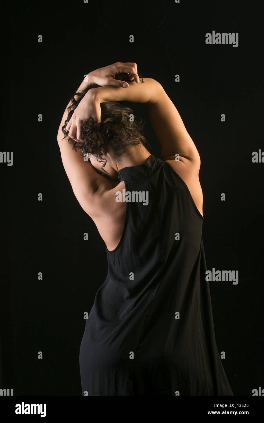 Rear view of a young woman wearing a black dress standing against a ...