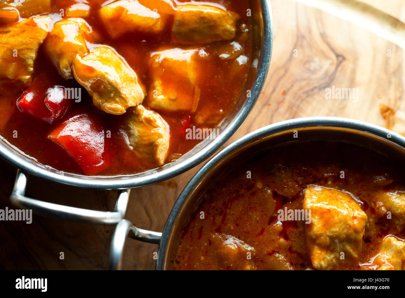 https://c8.alamy.com/comp/J43G70/close-up-view-from-above-of-curry-in-balti-dishes-on-a-wooden-slab-J43G70.jpg