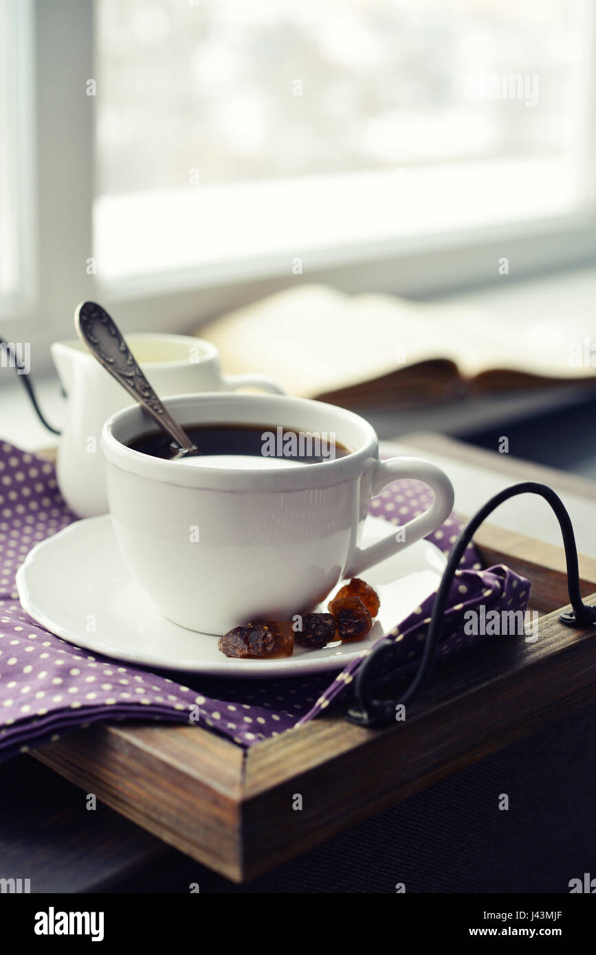 Cup of coffee on vintage tray on sofa with window on background Stock Photo