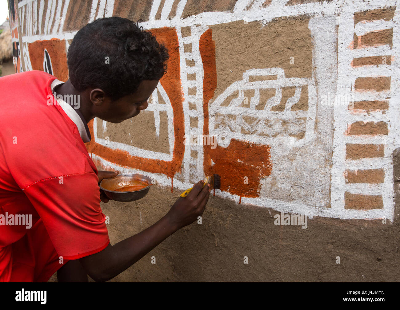 Young man painting the wall of a traditional ethiopian house, Kembata, Alaba Kuito, Ethiopia