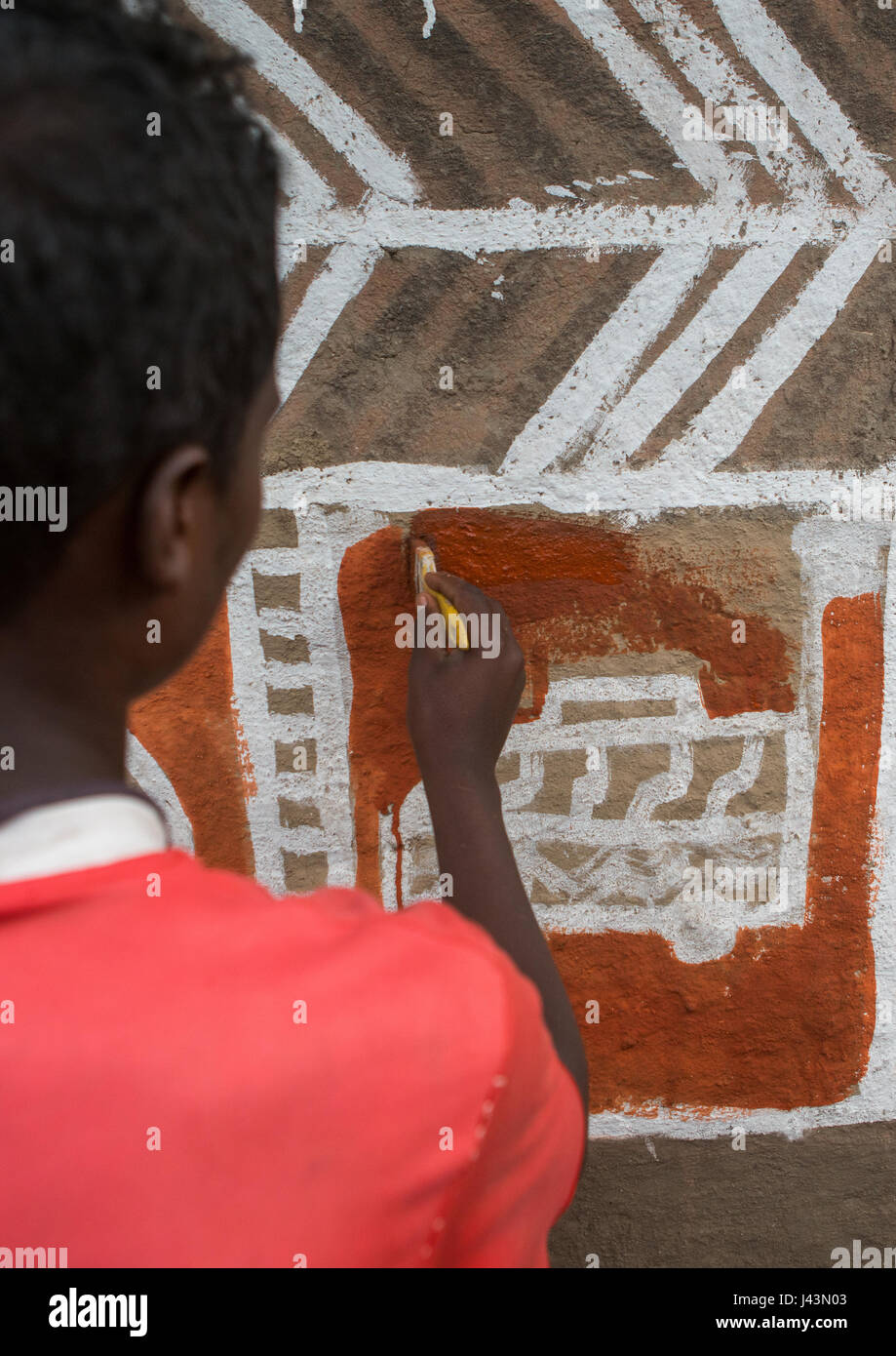 Young man painting the wall of a traditional ethiopian house, Kembata, Alaba Kuito, Ethiopia