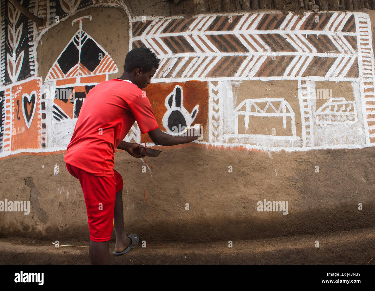 Young man painting the wall of a traditional ethiopian house, Kembata, Alaba Kuito, Ethiopia