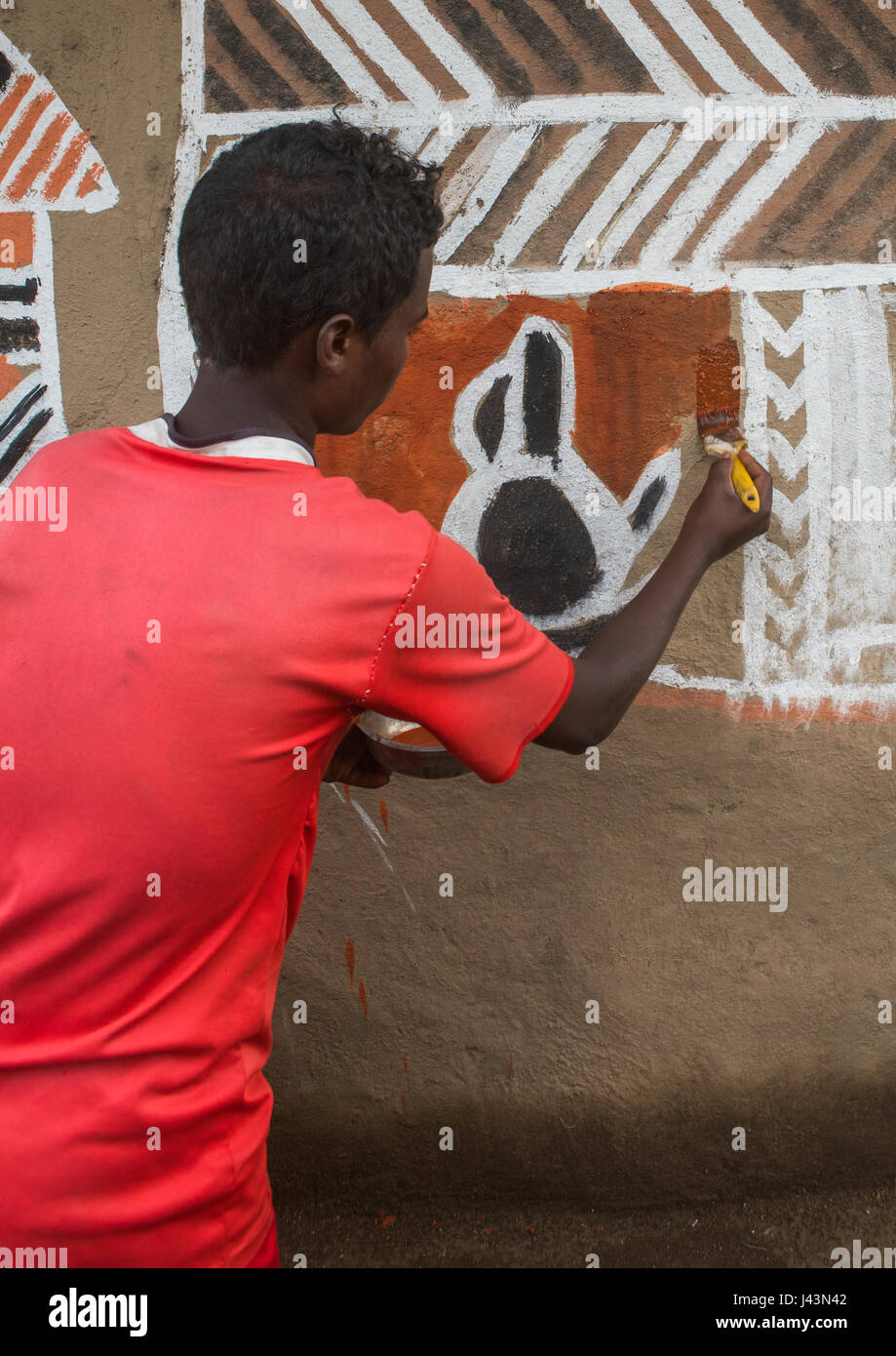 Young man painting the wall of a traditional ethiopian house, Kembata, Alaba Kuito, Ethiopia